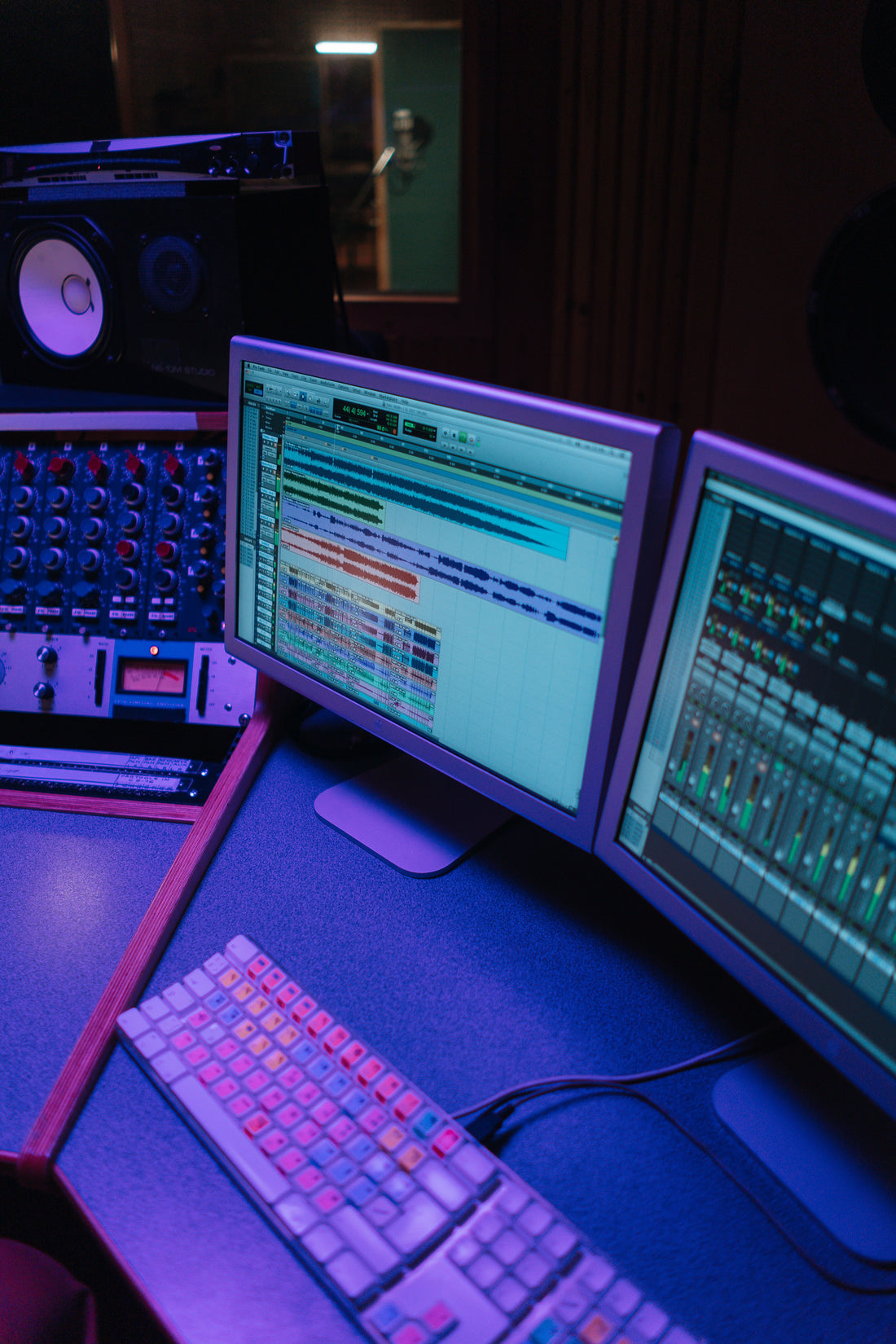Computer monitors displaying a digital audio workstation (DAW) during music production, representing the digital tools independent reggae and gospel artists use to build global music careers.